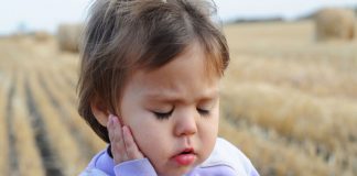 12 Effective Ear Pain Home Remedies for Children girl holding her ear