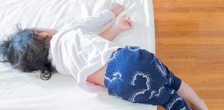 How to Deal with Baby Falling Off Bed Little girl sleeping on the bed with her legs dangling down the sides