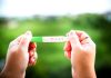 12 Effective Tips for Getting Pregnant with PCOS A woman holding a positive pregnancy test