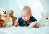 Your 26 Week Old Baby – Development, Milestones & Care A baby girl playing with soft toys in bed