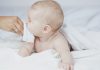10 Natural Remedies for Acid Reflux in Babies A mother wiping her baby's mouth